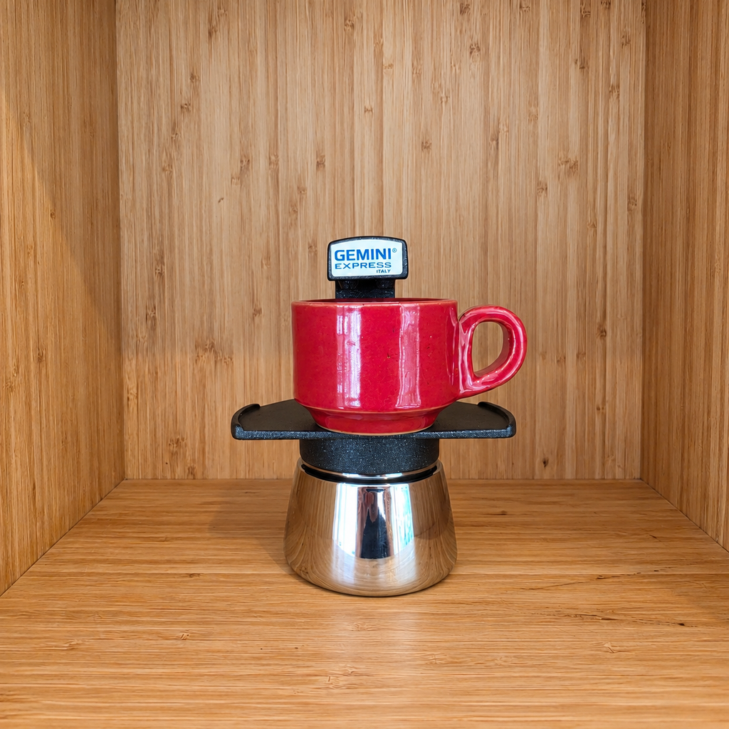 A Black Gemini Express moka pot centered with 1 red mug against a wooden background.