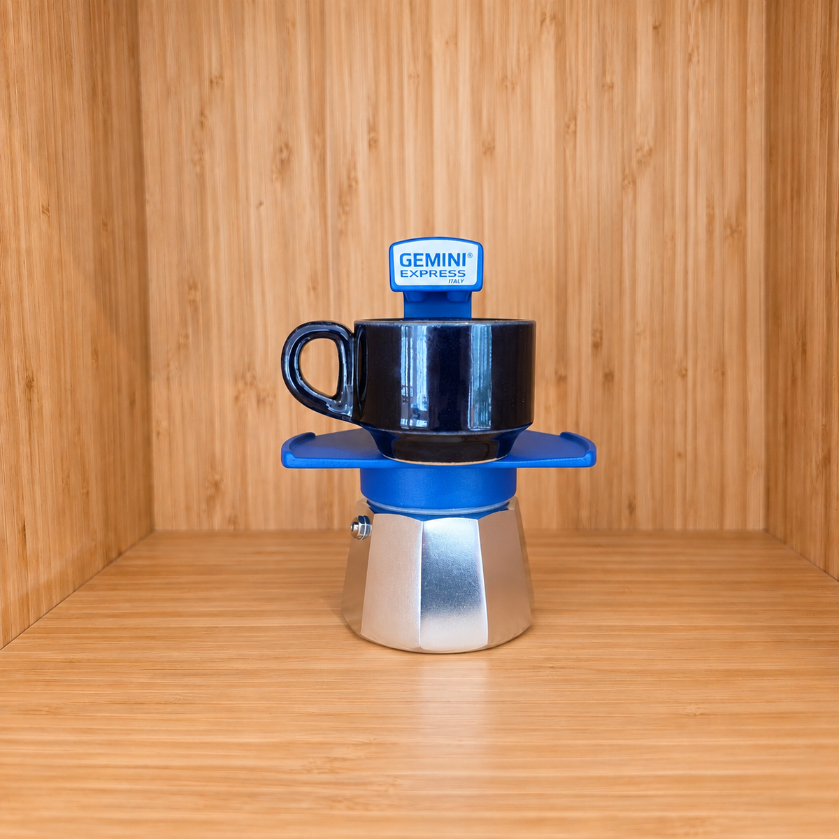 A blue Gemini Express Moka pot centered with 1 mug on a light wood grain surface against a matching wood grain background.