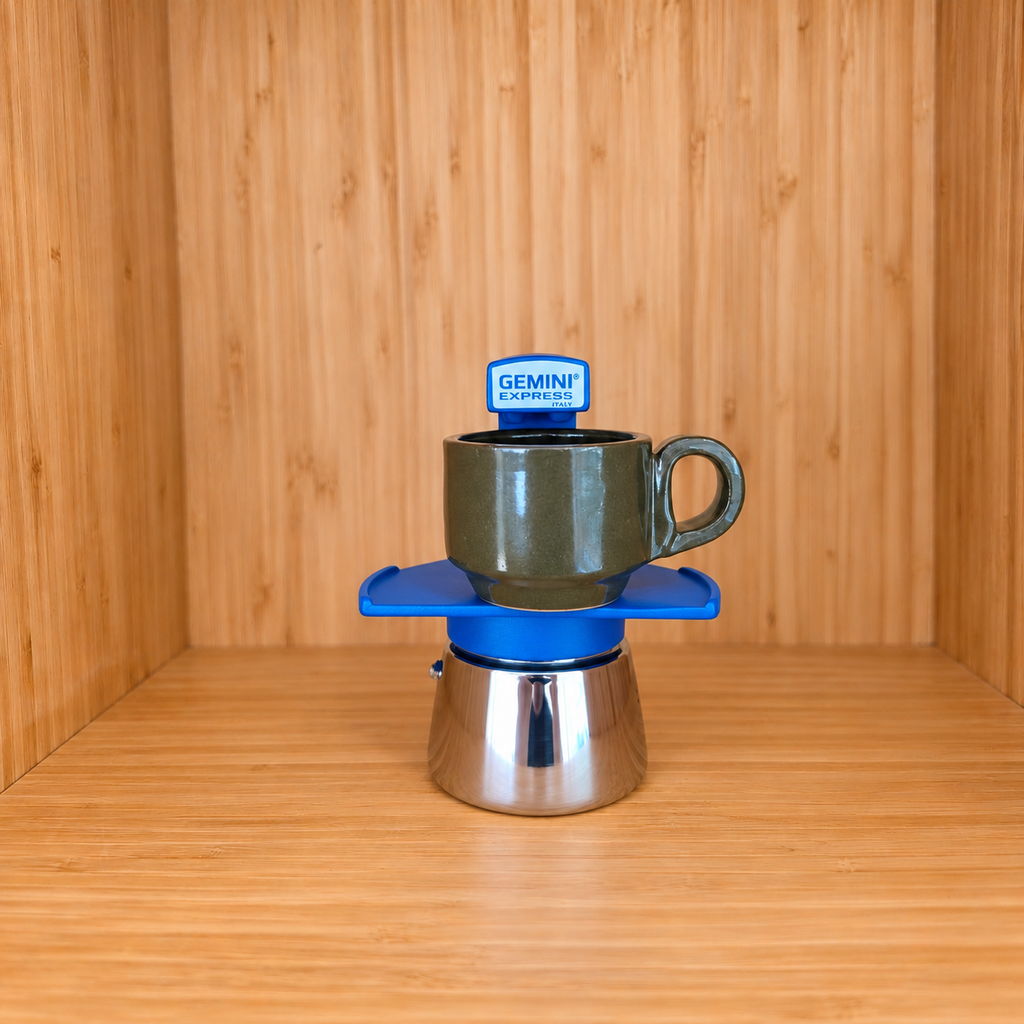 A blue Gemini Express Moka pot centered with 1 mug on a light wood grain surface against a matching wood grain background.