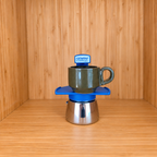 A blue Gemini Express Moka pot centered with 1 mug on a light wood grain surface against a matching wood grain background.