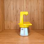 A Yellow Gemini Express espresso moka pot sideview on a wooden surface against a wooden wall background.